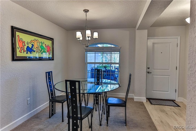 dining area featuring an inviting chandelier, light hardwood / wood-style floors, and a textured ceiling