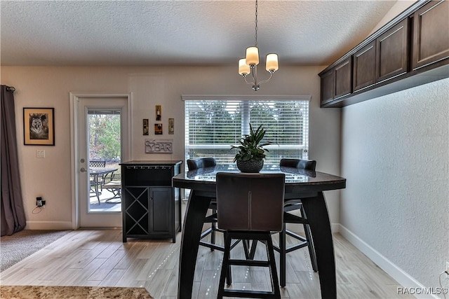 dining area with light hardwood / wood-style flooring, plenty of natural light, and a textured ceiling