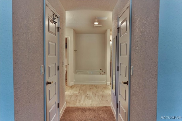 hallway with light hardwood / wood-style floors