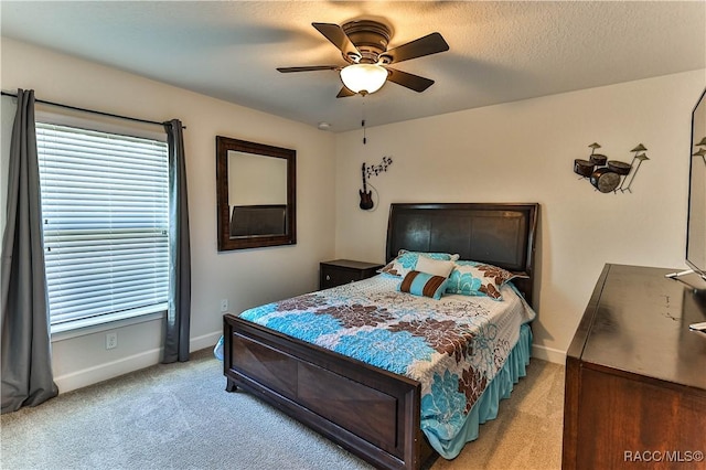 bedroom featuring ceiling fan, light carpet, and a textured ceiling