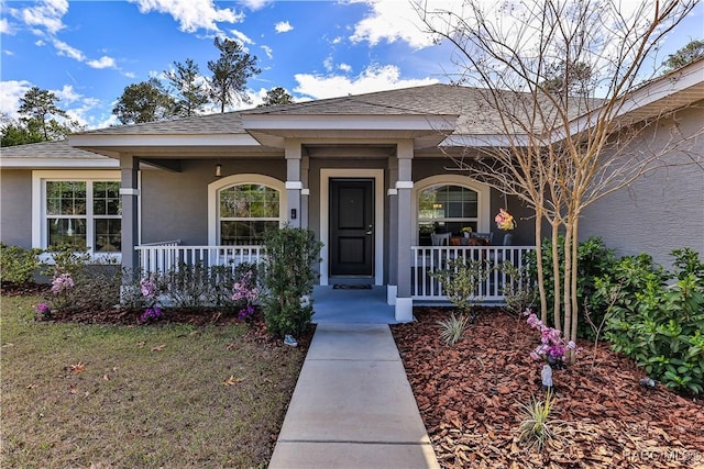 entrance to property with a porch and a yard