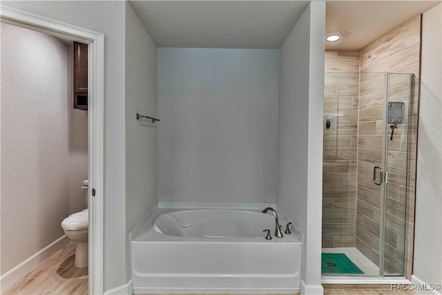 bathroom with hardwood / wood-style flooring, a textured ceiling, independent shower and bath, and toilet