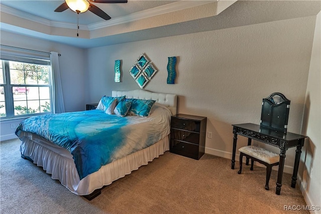 bedroom with a tray ceiling, ornamental molding, ceiling fan, and carpet flooring