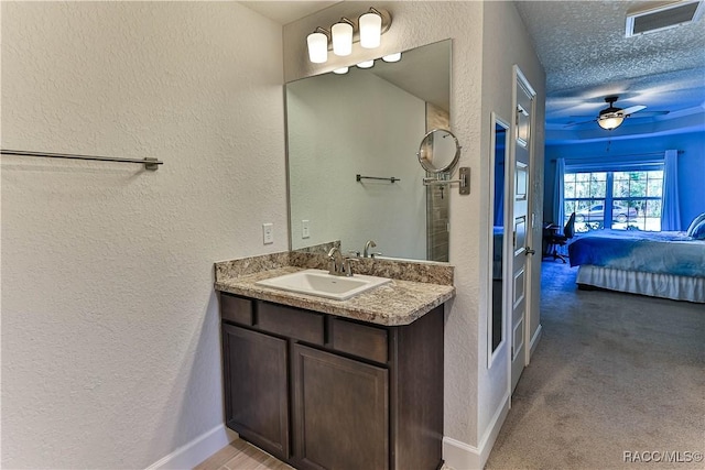 bathroom with ceiling fan, vanity, and a textured ceiling