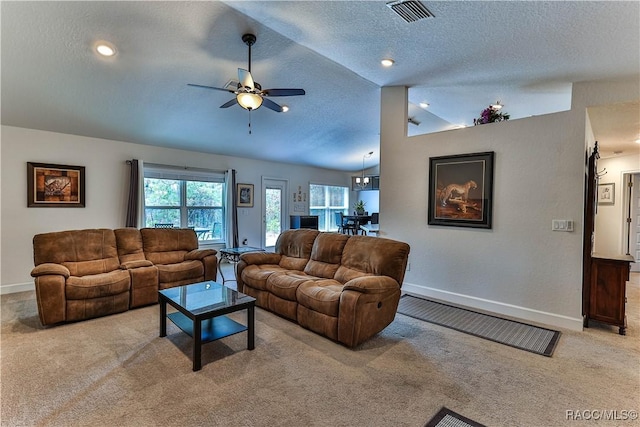 living room with ceiling fan, lofted ceiling, light carpet, and a textured ceiling