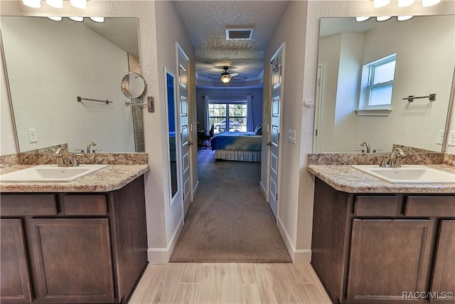 bathroom featuring vanity, ceiling fan, wood-type flooring, and a textured ceiling