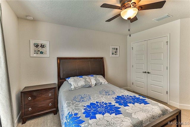 bedroom with ceiling fan, light carpet, a textured ceiling, and a closet