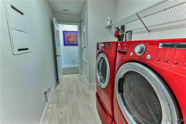 laundry room featuring washing machine and clothes dryer and light hardwood / wood-style flooring