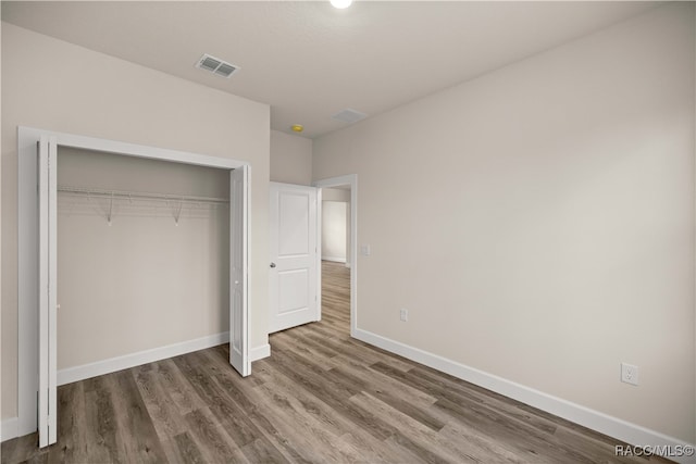 unfurnished bedroom with hardwood / wood-style flooring and a closet