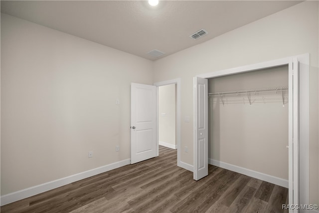 unfurnished bedroom featuring a closet and dark hardwood / wood-style floors