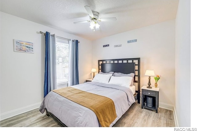 bedroom with ceiling fan, light hardwood / wood-style floors, and a textured ceiling