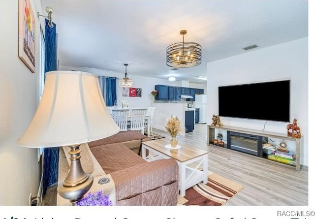 living room with a chandelier and light hardwood / wood-style floors