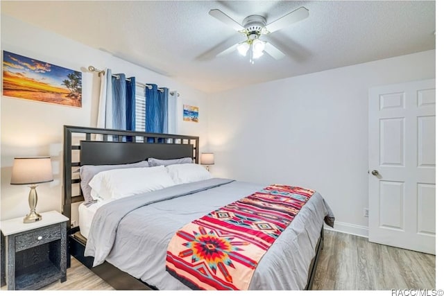 bedroom featuring ceiling fan, wood-type flooring, and a textured ceiling