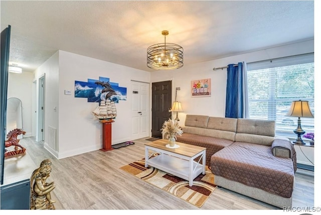 living room featuring wood-type flooring, a textured ceiling, and an inviting chandelier