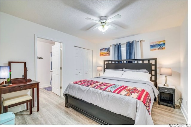 bedroom with a closet, light hardwood / wood-style flooring, ceiling fan, and a textured ceiling