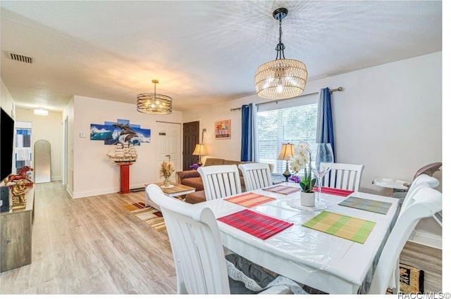 dining area with light wood-type flooring and a notable chandelier