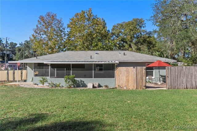 rear view of property with a sunroom and a lawn