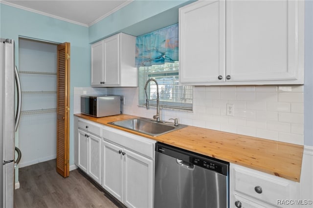 kitchen featuring light wood-type flooring, ornamental molding, stainless steel appliances, sink, and white cabinets