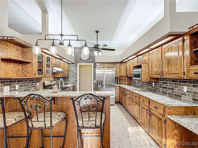 kitchen with a breakfast bar area, decorative backsplash, ceiling fan, kitchen peninsula, and stainless steel appliances