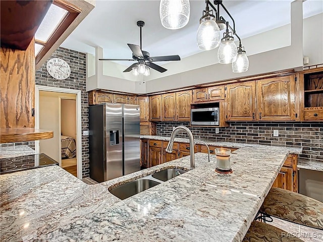 kitchen featuring ceiling fan, sink, stainless steel appliances, a kitchen bar, and decorative backsplash