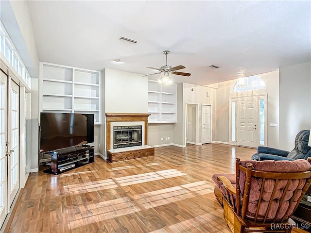 living room featuring hardwood / wood-style flooring, built in features, and ceiling fan