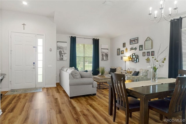 dining area with light wood-type flooring and an inviting chandelier