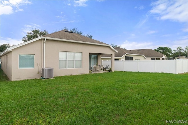 back of house featuring central AC unit, a patio area, and a lawn