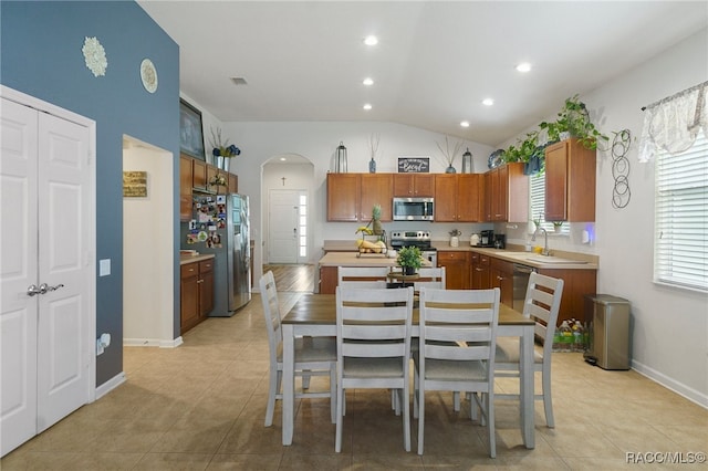 kitchen featuring a center island, sink, lofted ceiling, light tile patterned floors, and appliances with stainless steel finishes