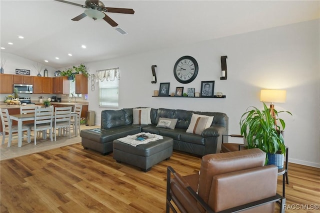 living room with ceiling fan, light hardwood / wood-style flooring, lofted ceiling, and sink