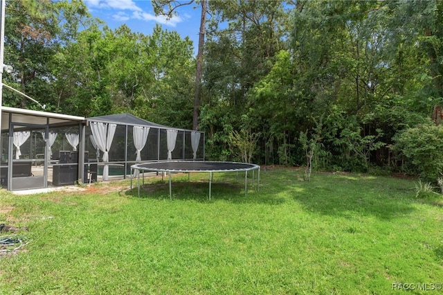 view of yard featuring a sunroom and a trampoline