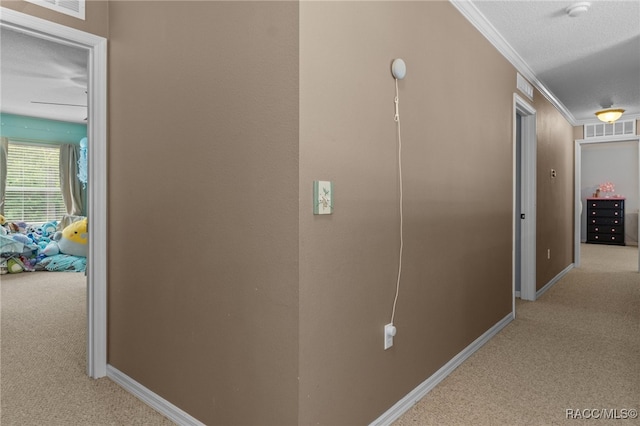 hallway featuring a textured ceiling, light colored carpet, and crown molding