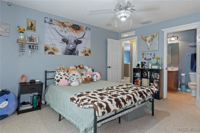 bedroom featuring light colored carpet, ceiling fan, and ensuite bathroom