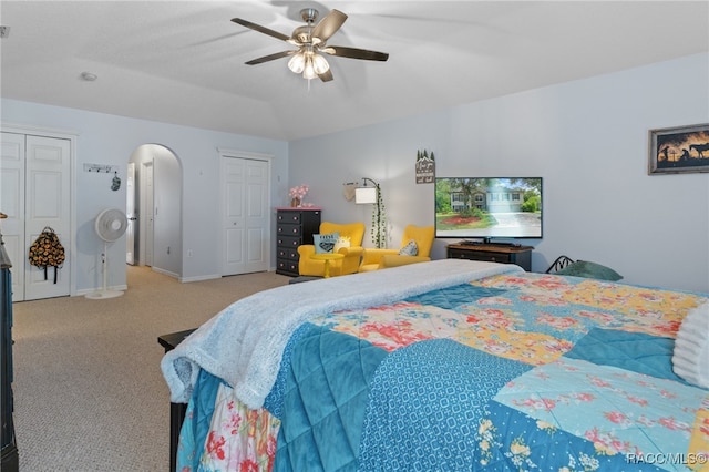 bedroom featuring multiple closets, ceiling fan, and light colored carpet