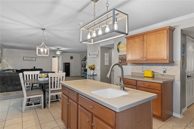 kitchen with sink, ceiling fan, ornamental molding, and a kitchen island with sink