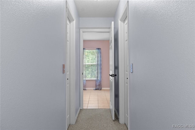 corridor with light carpet and a textured ceiling