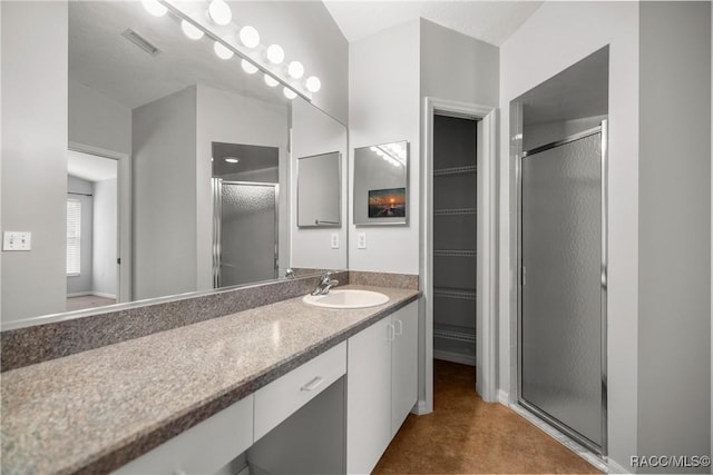 full bath featuring visible vents, vanity, concrete flooring, a walk in closet, and a stall shower