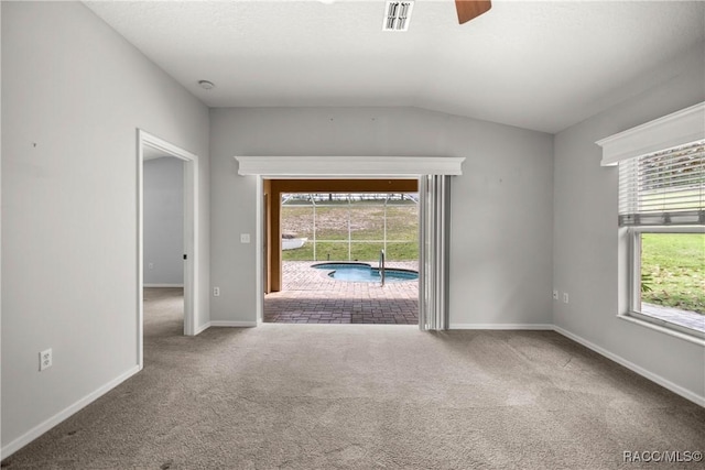 spare room featuring visible vents, carpet flooring, ceiling fan, and a wealth of natural light