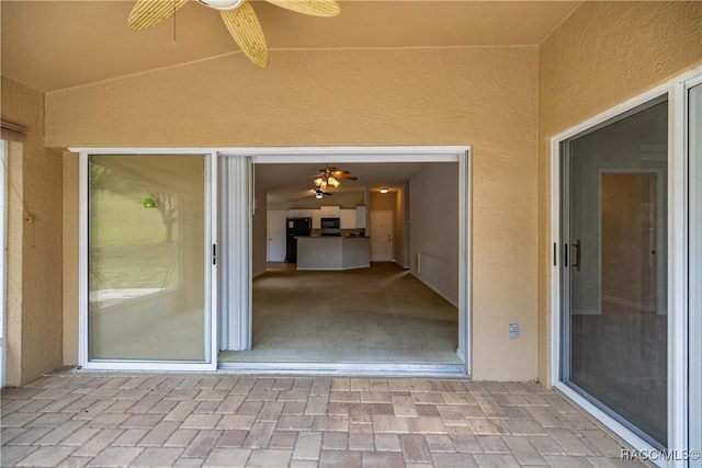 exterior space with a ceiling fan and stucco siding