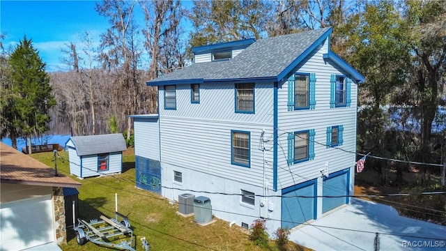 view of home's exterior with a storage shed, a garage, a lawn, and central air condition unit