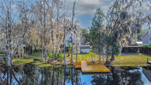 view of dock with a water view and a yard