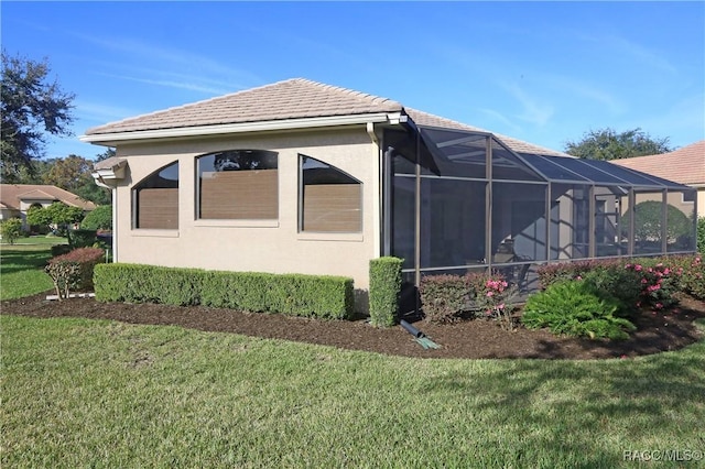 view of side of home with a yard and a lanai