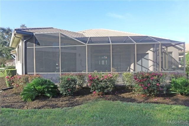 rear view of property featuring glass enclosure