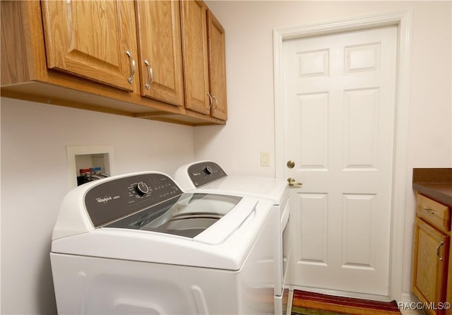 laundry area with washing machine and clothes dryer and cabinets