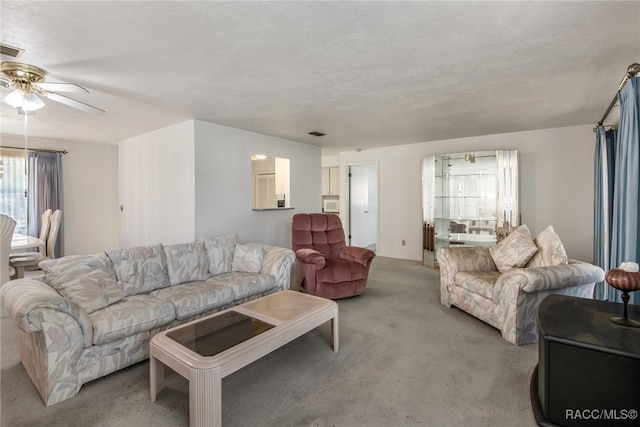 living room with light carpet, ceiling fan, and a textured ceiling