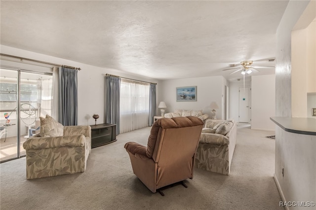 living room featuring ceiling fan, light colored carpet, and a textured ceiling