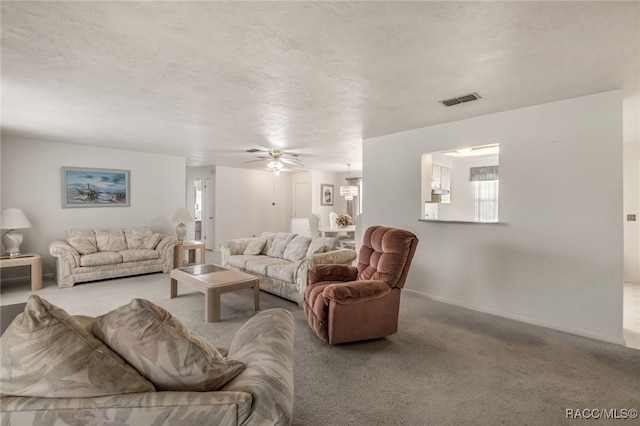 living room with carpet flooring, ceiling fan, and a textured ceiling