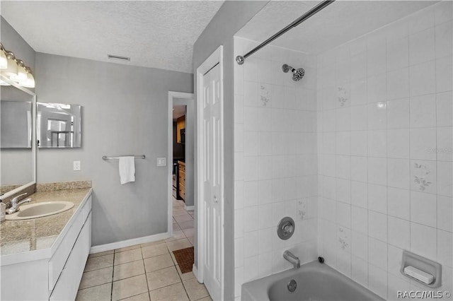 bathroom with a textured ceiling, vanity, tiled shower / bath, and tile patterned flooring