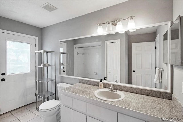 bathroom with vanity, toilet, a shower, and tile patterned flooring