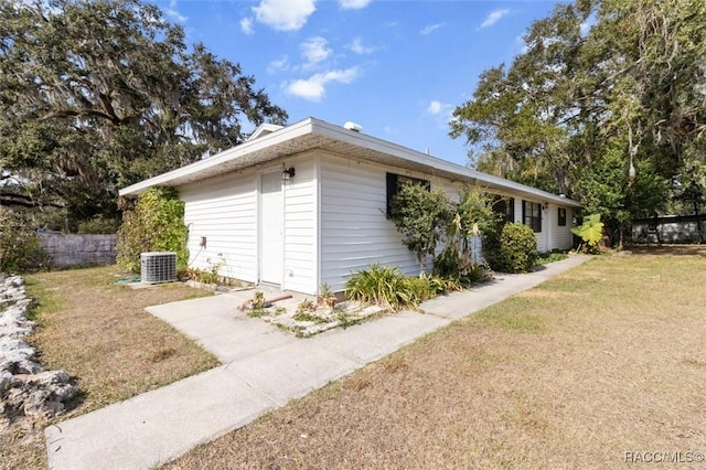 view of side of home featuring a lawn and central AC