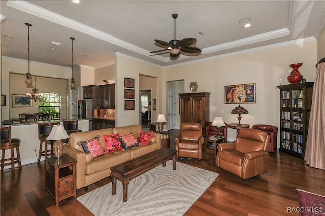 living room with a tray ceiling, crown molding, dark hardwood / wood-style flooring, and ceiling fan with notable chandelier